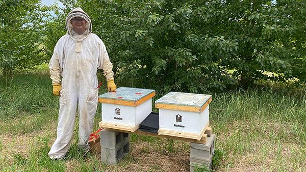 Man posing with honeybee hives